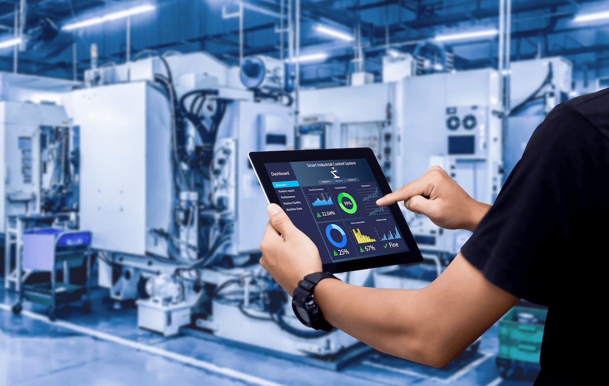 Obrazek przedstawiający wielką firmę wraz z pracownikiem trzymającym tablet, który prezentuje wykresy